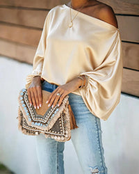 Satijnen damesblouse met asymmetrische off-shoulder halslijn en brede vleermuismouwen